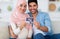 Happy arab family demonstrating ultrasound scan and smiling to camera, sitting on sofa at home