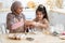 Happy arab mom and her little daughter kneading dough together in kitchen