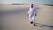 Happy Arabian UAE sheikh man walks in middle of white desert and enjoys life on hot summer day.
