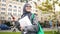 Happy arabic female on street, holding smartphone and notebooks in hand, student