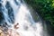 Happy asian boy playing in freshwater of tropical waterfall in summer