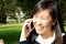 Happy asian business woman relaxing talking on the phone in park smiling extreme closeup