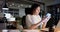 Happy asian casual businesswoman at desk using smartphone in office at night, slow motion