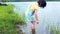 Happy asian child having fun and kicking water at lake