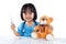 Happy Asian Chinese little girl examine teddy bear with thermometer