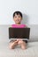 Happy Asian Chinese little girl sitting on sofa with laptop