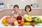 Happy Asian Chinese little sisters eating fruit and vegetable