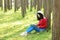 Happy Asian Chinese woman beauty girl smile and read a book in forest spring park lean on a tree