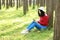 Happy Asian Chinese woman beauty girl smile and read a book in forest spring park lean on a tree