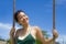 Happy Asian Chinese woman holding swing rope having fun on a Summer blue sky smiling positive and cheerful in holidays