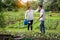 Happy asian couple gardeners,wife help,care,wipe sweat for  husband in farm,man working using rake in organic garden,woman with