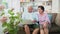 Happy Asian couple sitting on sofa and using a laptop to surf the internet and VIDEO conference with family. Concept of technology