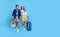 Happy Asian couple tourist hand pointing to copy space with baggage going to travel on holidays isolated on blue background