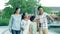 Happy asian family of 4 pointing & walking toward camera in slow motion