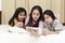 Happy Asian family enjoy and relax on bed in bedroom. mother and daughters enjoy using tablet together on bed.  Family concept