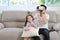 Happy Asian family, father and daughter playing virtual reality goggles on the sofa in the living room with happy smiling face