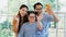 Happy Asian family father mother and handicapped daughter with down syndrome standing and smiling at a camera in a living room at