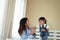 Happy Asian family loving children, kid and her sister holding microphone and singing together on bed in bedroom