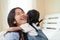 Happy Asian family loving children, kid hugging her sister, relaxing together in bed