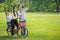 happy asian Family, parents and children riding bike hands up in park together. father ,mother ,son on bicycle  having fun