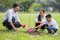 happy asian Family, parents and their children plant sapling tree together in park . father mother and son,boy having fun and