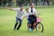 happy asian Family, parents and their children riding bike in park together. father pushes  mother and son on bicycle having fun