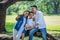 happy asian Family, parents and their children taking selfie in park together. father, mother ,son sitting on branch of big tree