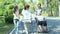 Happy asian family,senior woman, disabled grandmother with walker and wheelchair, daughter,teen granddaughter enjoying a walk in o