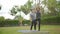 Happy asian father doing training exercises to mother on yoga mat in grass park at the day time