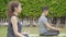 Happy asian father doing training exercises to mother on yoga mat in grass park at the day time