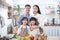 Happy asian father,mother,child standing and smile in kitchen.Healthy parent prepare salad