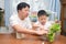 Happy Asian father and son having fun cutting a piece of a plant, Introduce scissor skills for children, Homeschooling, home