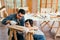 Happy Asian father and son work as a woodworker and carpenter. Father teaching his son to hammer nails on a wooden plank carefully