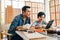 Happy Asian father and son work as a woodworker and carpenter, watching content on a digital tablet for making a new woodwork