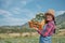 Happy Asian Female farmer with big smile carries a basket of cabbage in the field