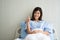 Happy Asian female patient smiling, lies on the bed, and raises thumb up to show confidence in treatment. Concept of believe in