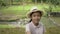 Happy asian female teenager wearing straw hat taking a selfie portrait while standing near the creek at forest park.