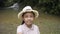 Happy asian female teenager wearing straw hat taking a selfie portrait while standing near the small waterfall.