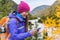 Happy asian girl in cold weather gear hiking in nature using smartphone with touch screen gloves during hike in autumn travel