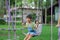 Happy Asian girl having fun playing in the playground during summer. Cute little girl swinging in the playground with a smile and