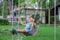 Happy Asian girl having fun playing in the playground during summer. Cute little girl swinging in the playground with a smile and