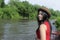 Happy Asian girl red shirt and brown hat on the river in nature