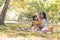 Happy Asian grandmother telling story, reading fairly tales to her adorable granddaughter while picnicking in the