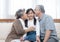 Happy asian grandparents sitting on sofa at home playing and kiss on cheek of little granddaughter