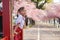 Happy Asian kindergarten little girl in garden under the blossom sakura tree