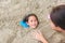 Happy asian little child girl buried in the sand at the beach by mother. Kid playing with sand at holiday with family