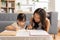 Happy Asian little girl doing homework with mother at home. Asian young mother teaching small daughter to drawing reading and
