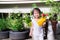 Happy Asian little girl stands in front of her house holding a yellow watering can to help with some household chores and