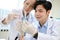 Happy Asian male scientist and senior female supervisor looking at the test tubes together