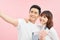 Happy asian man and woman holding passports and air tickets while looking at camera isolated on pink